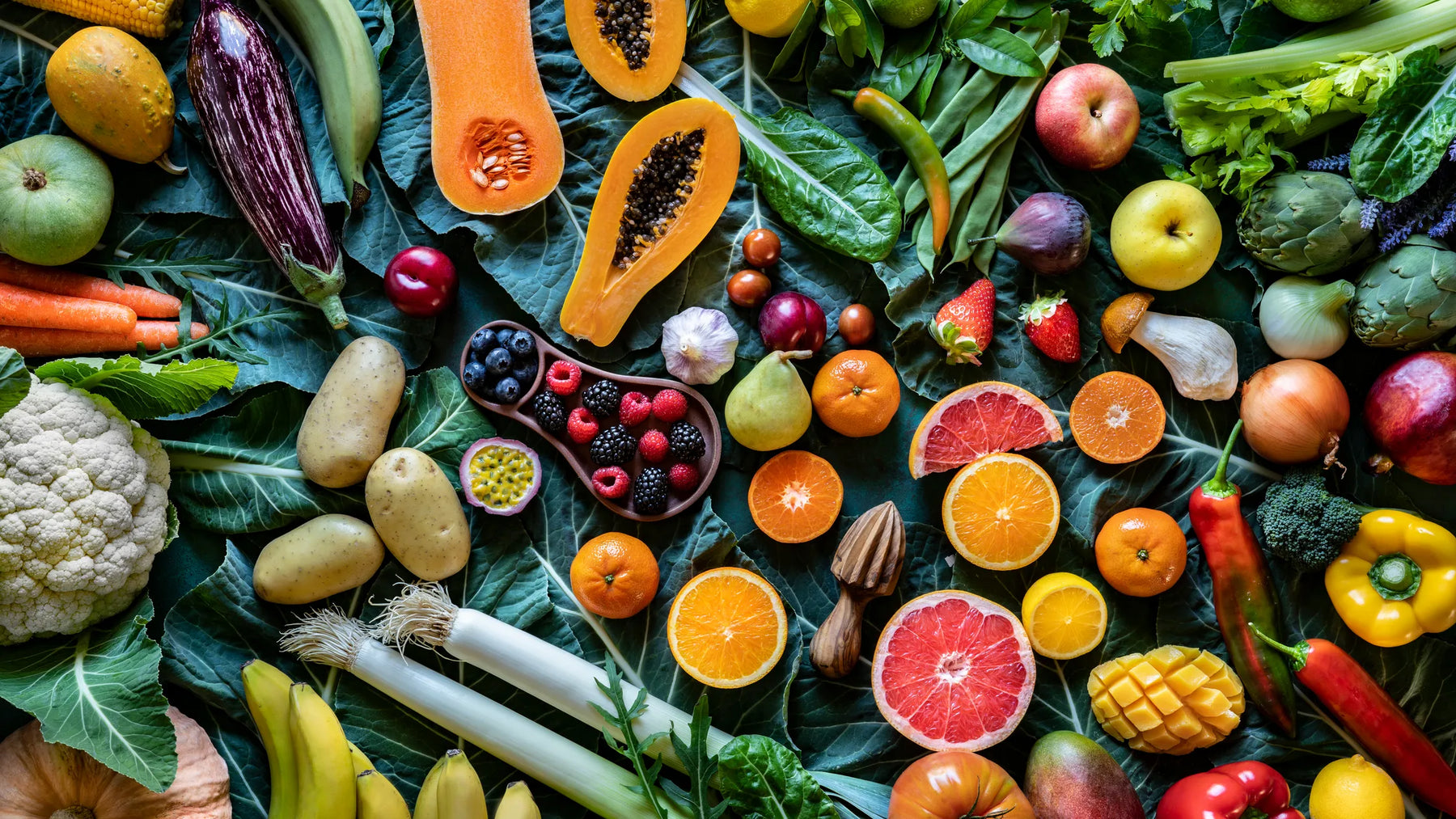 Fruits et légumes colorés étalés sur des feuilles vertes, symbolisant une alimentation équilibrée face à la diète cétogène