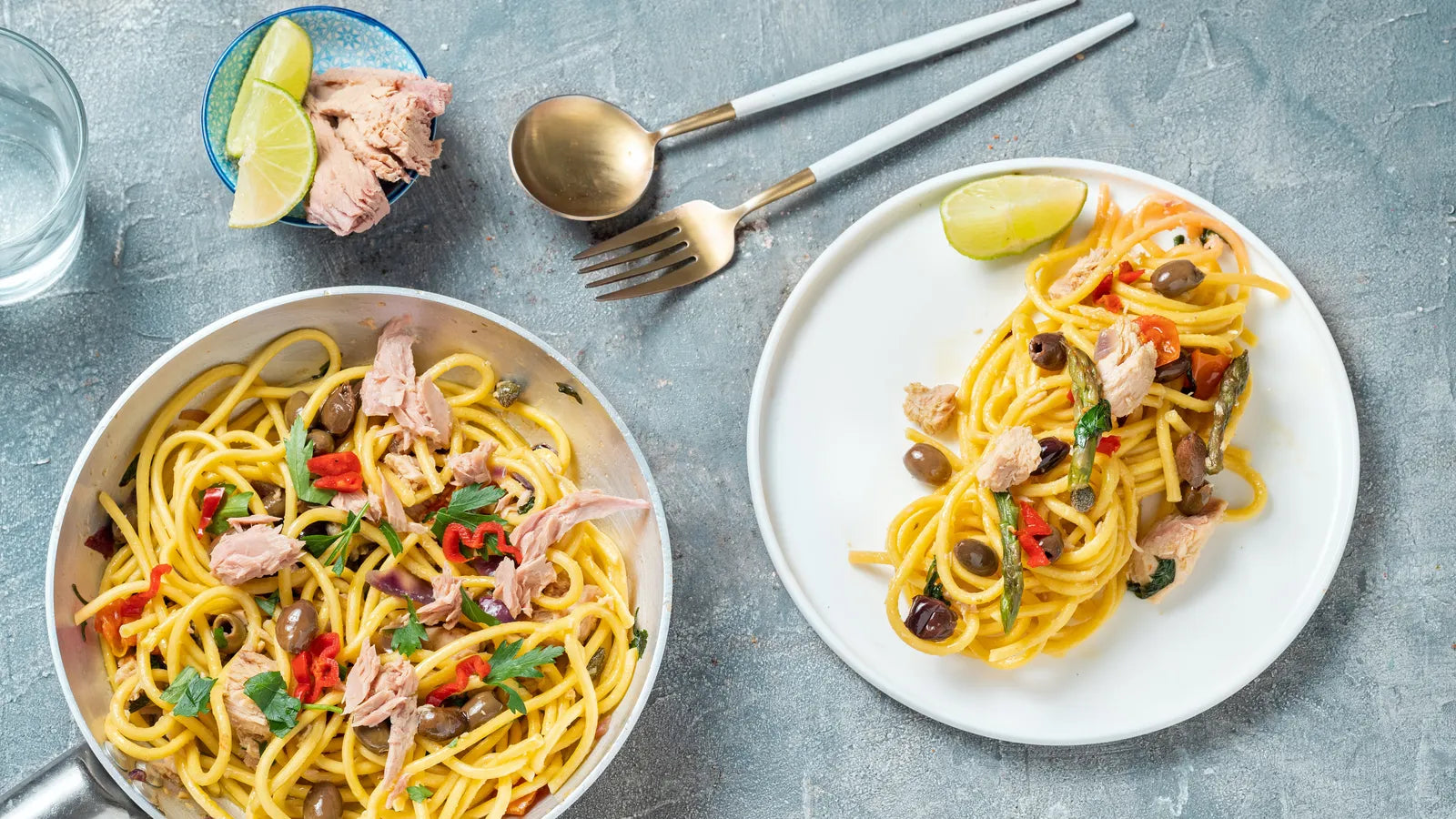 Pasta al tonno dans une poêle et une assiette avec thon, olives, piments et citron vert