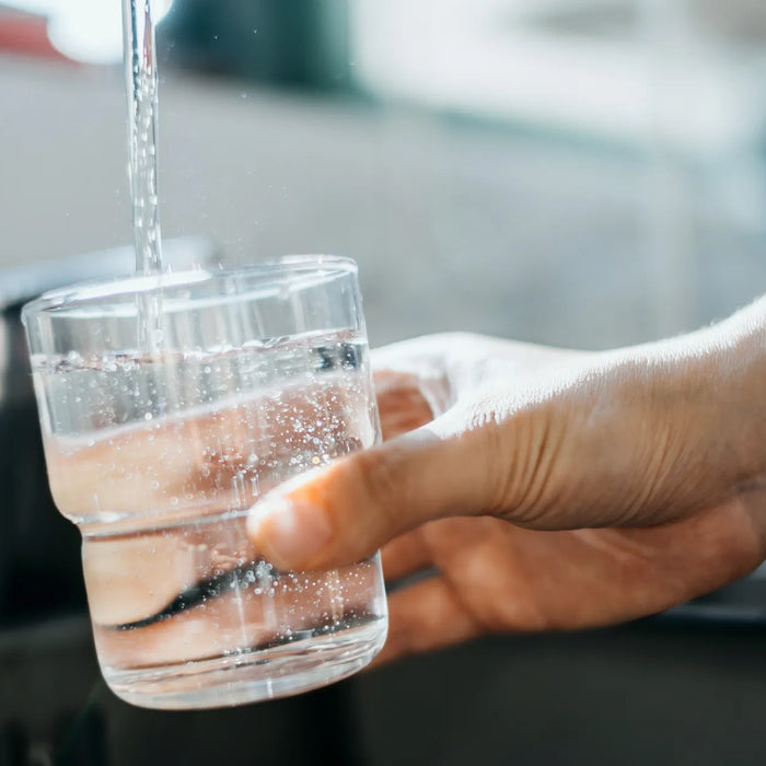 Verre d’eau du robinet rempli à l’évier – symbole d’eau potable contrôlée et sûre à domicile