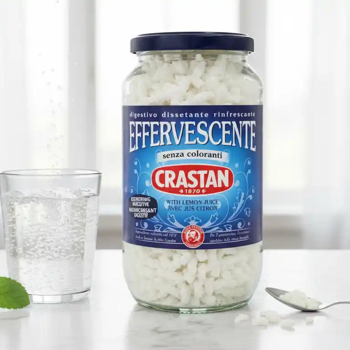 Pot de granulés Crastan Effervescents posé à côté d’un verre d’eau pétillante et de feuilles de menthe, remède digestif italien naturel.