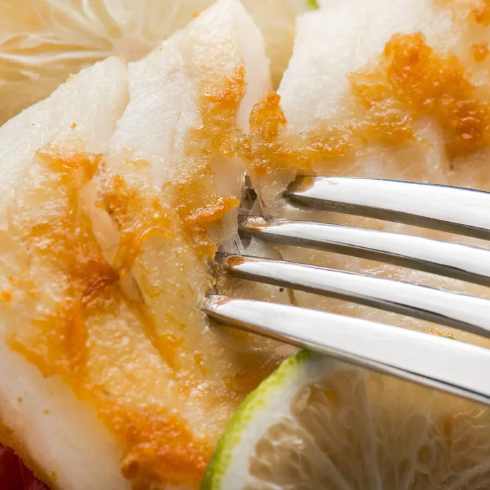 Filet de poisson blanc délicatement doré, accompagné de rondelles de citron vert et de tomates, un plat sain et savoureux idéal pour la période de Carême.