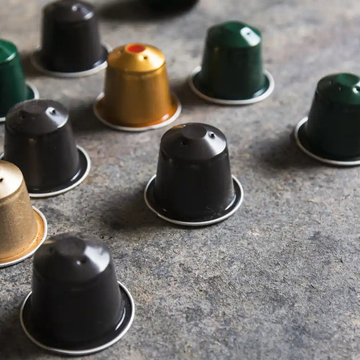Capsules Nespresso de différentes couleurs disposées sur un plan de travail, illustrant le concept de café réutilisable et durable.