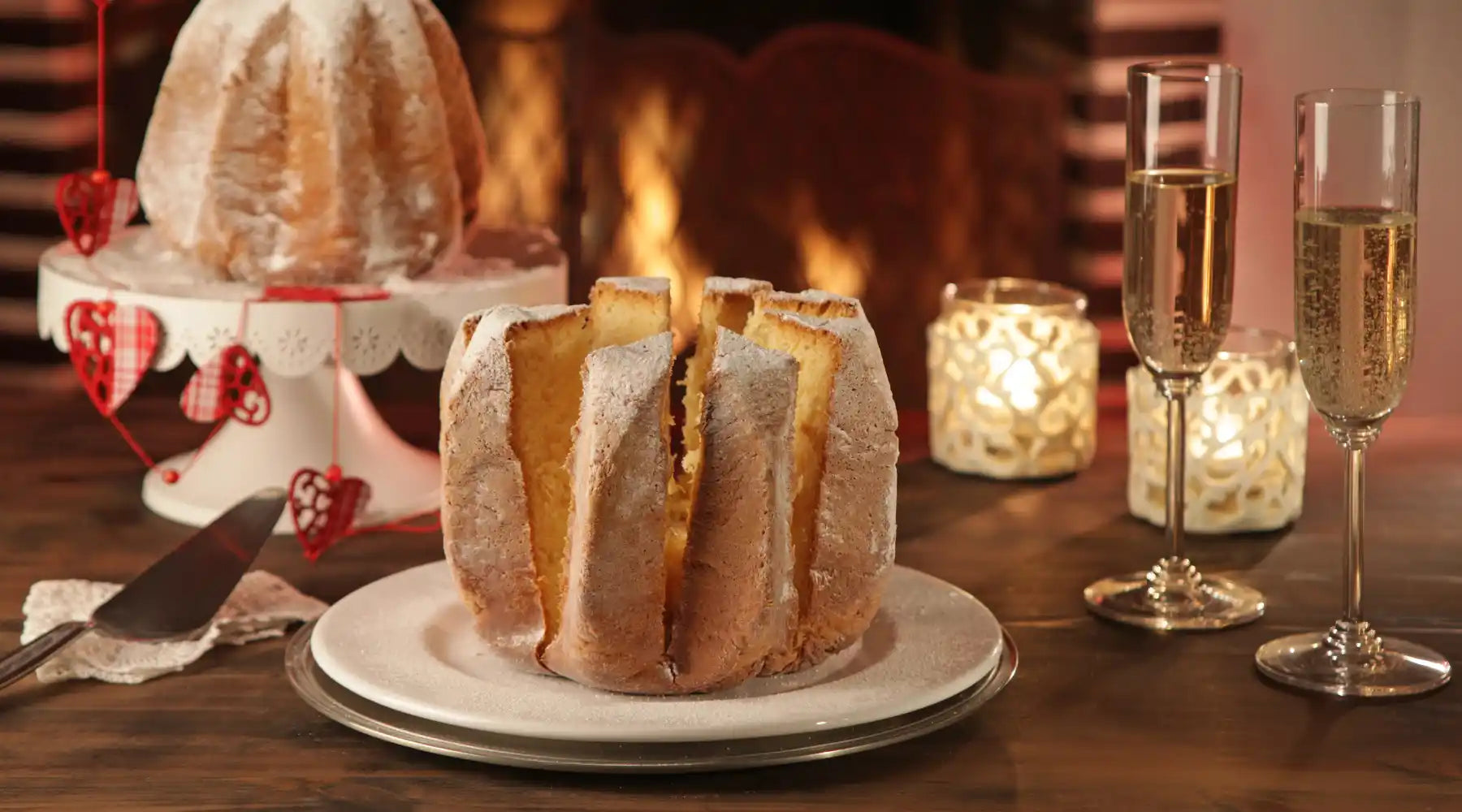 pandoro italien tranché servi sur une table festive avec bougies et verres de champagne devant une cheminée