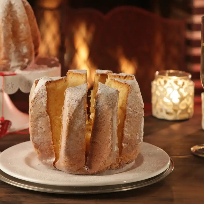 pandoro italien tranché servi sur une table festive avec bougies et verres de champagne devant une cheminée