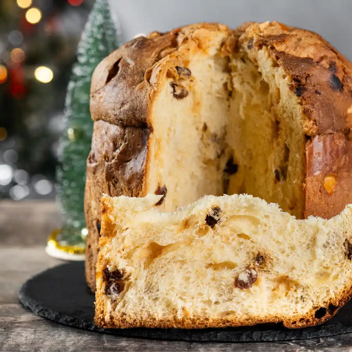Panettone traditionnel posé sur une table en bois, coupé pour révéler sa texture moelleuse.