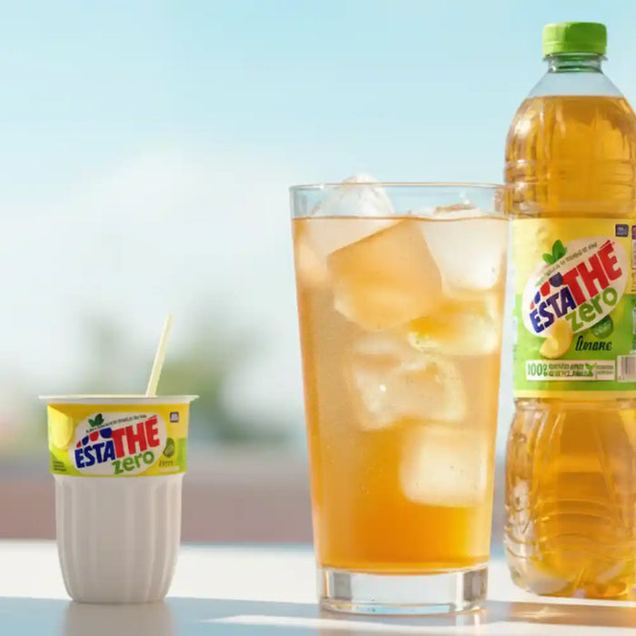 Verres et bouteilles de thé glacé Estathé Zero aux saveurs citron et pêche posés sur une table lumineuse.