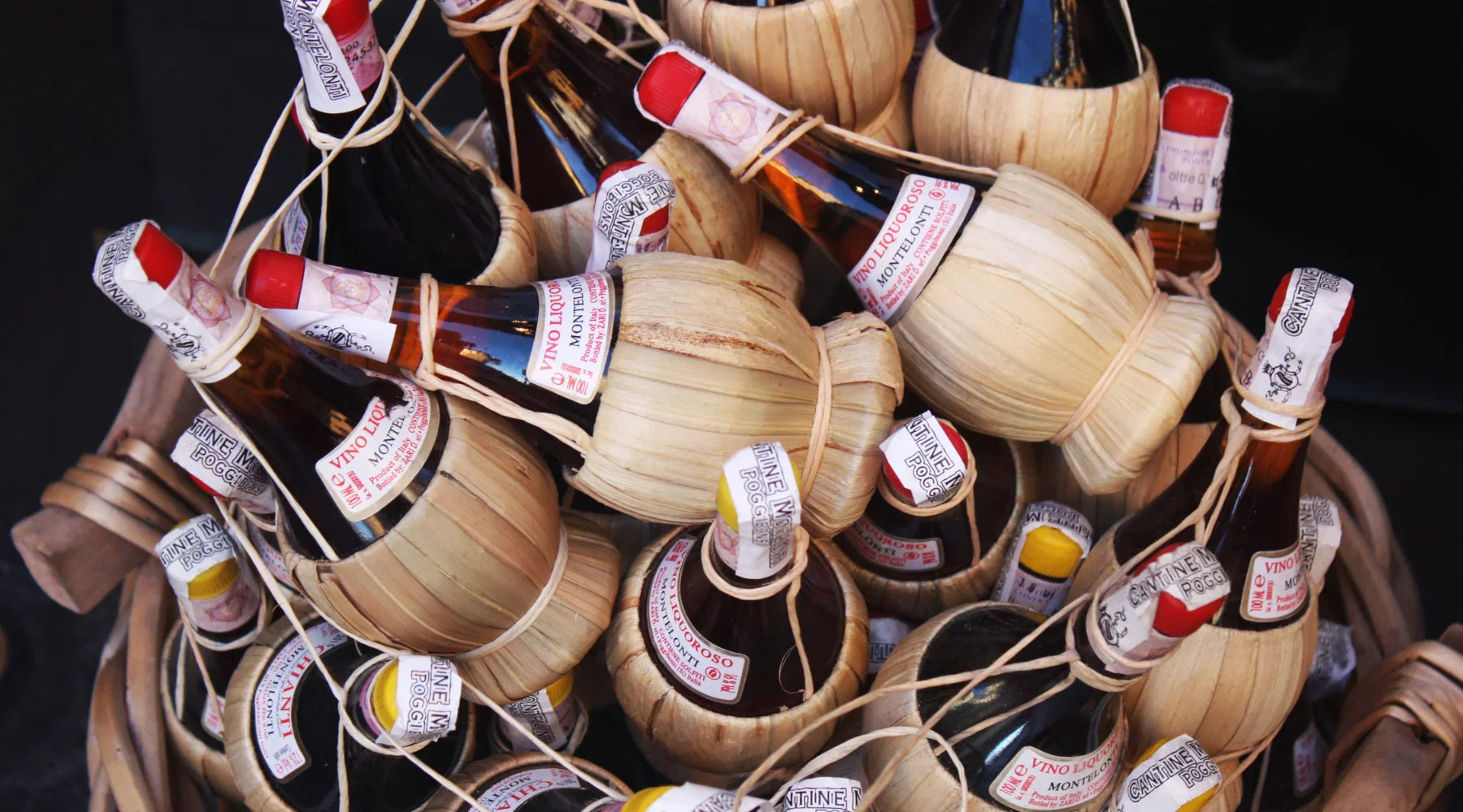 Bouteilles traditionnelles de vin Chianti enveloppées de paille dans un panier, symbolisant l’artisanat et l’authenticité des vins toscans.