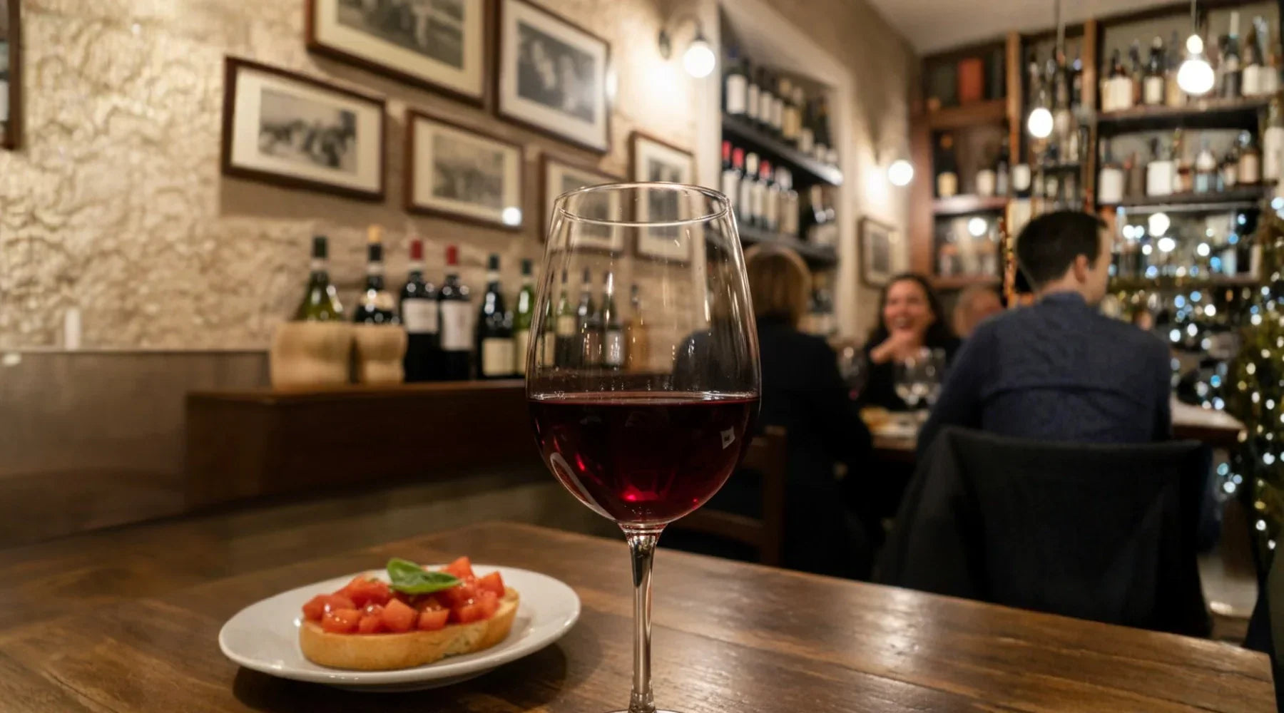 Verre de vin rouge Valpolicella sur une table de restaurant italien, accompagné d’une bruschetta, avec des bouteilles en arrière-plan, illustrant l’art de vivre et la convivialité italienne.