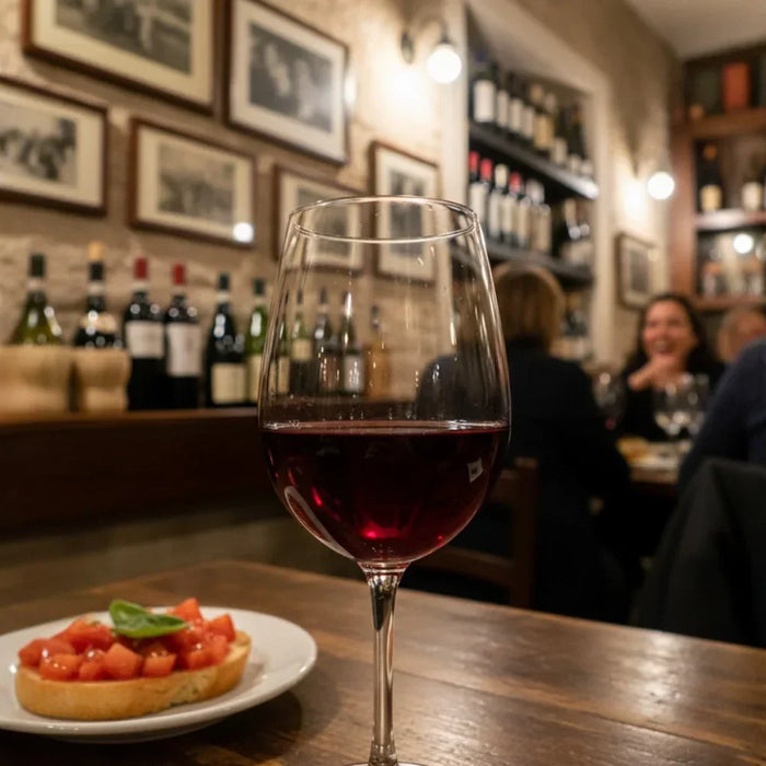 Verre de vin rouge Valpolicella sur une table de restaurant italien, accompagné d’une bruschetta, avec des bouteilles en arrière-plan, illustrant l’art de vivre et la convivialité italienne.