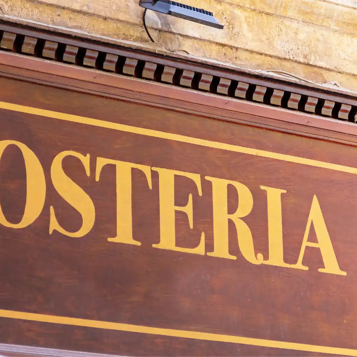 Panneau en bois traditionnel avec l’inscription « OSTERIA », typique des auberges italiennes authentiques.