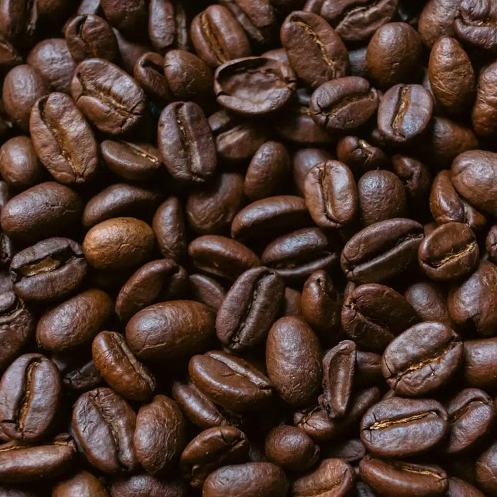 Grains de café torréfiés vus de près, texture brillante et couleur brun foncé, symbolisant un café italien de qualité.