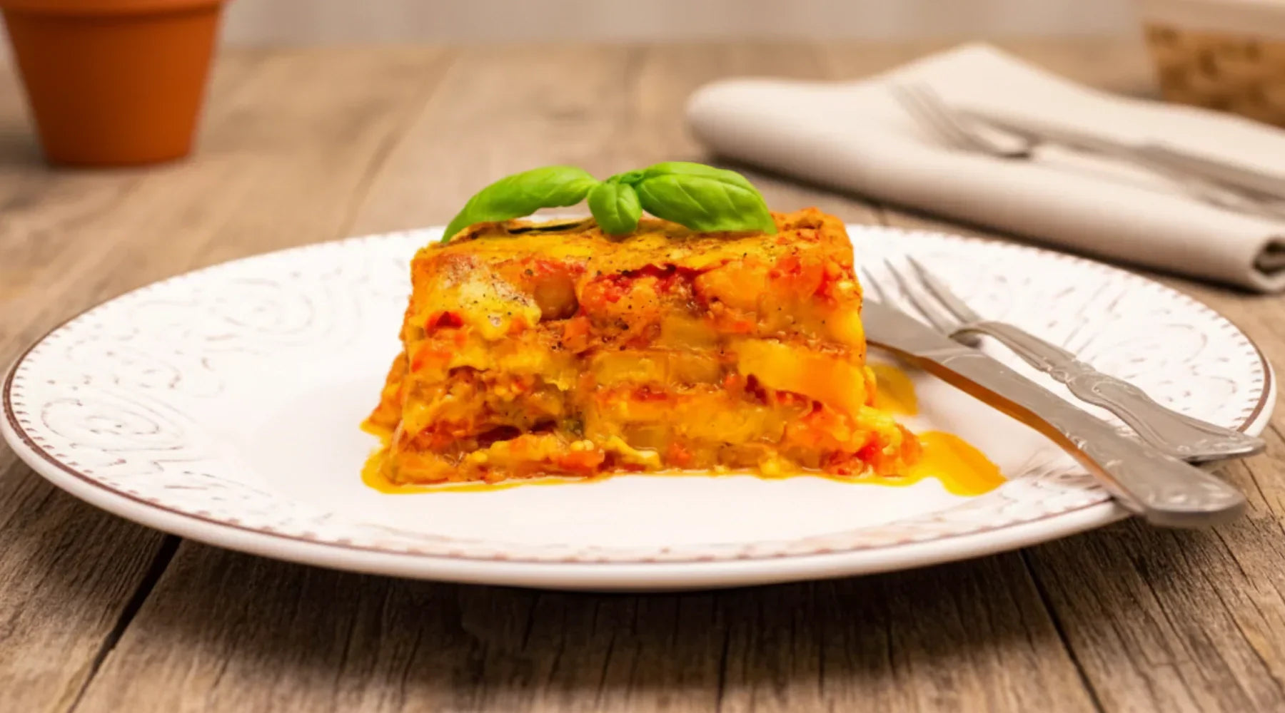 Parmigiana de courge servie chaude sur assiette blanche, gratinée à la sauce tomate, au parmesan et garnie de basilic frais