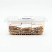 Transparent container of Italian millefoglie D'Addezio, consisting of layers of crispy puff pastry filled with hazelnut cream, presented on a white background.