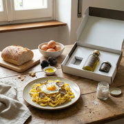 Truffle box La Dolce Vita by Montosco placed on a table with fresh pasta, fried egg, and truffle condiments